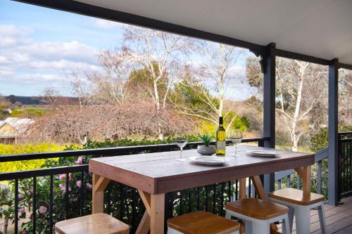 a table with glasses of wine on a balcony at Aggies Way - dog friendly with panoramic views in Daylesford