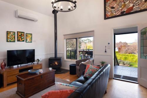 a living room with a couch and a tv at Aggies Way - dog friendly with panoramic views in Daylesford