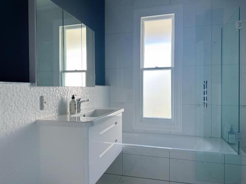 a bathroom with a tub and a sink and a mirror at The Ultimate Escape - Holiday Villa Private POOL in Auckland