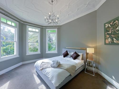 a bedroom with a large bed with white sheets and windows at The Ultimate Escape - Holiday Villa Private POOL in Auckland