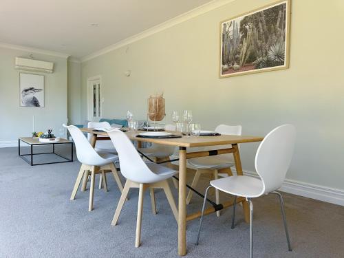 a dining room with a wooden table and white chairs at The Ultimate Escape - Holiday Villa Private POOL in Auckland