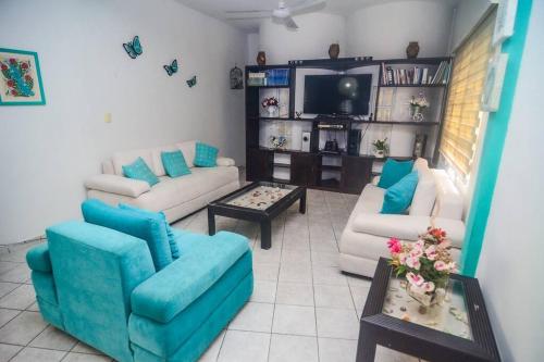 a living room with two couches and a tv at Casa con alberca y amplio espacio para tu familia in Playa del Carmen