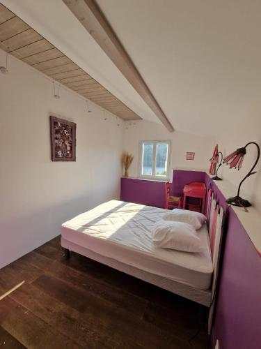 une chambre avec un grand lit aux murs violets dans l'établissement Maison au bord de l'eau, à Saint-Priest-la-Roche