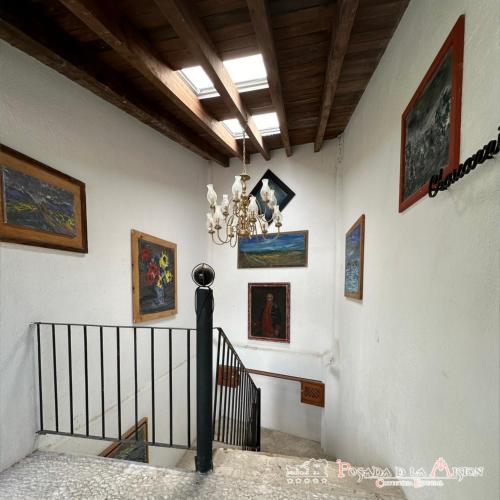 a staircase with a chandelier and paintings on the wall at Posada de la Mision, Hotel Museo y Jardin in Taxco de Alarcón