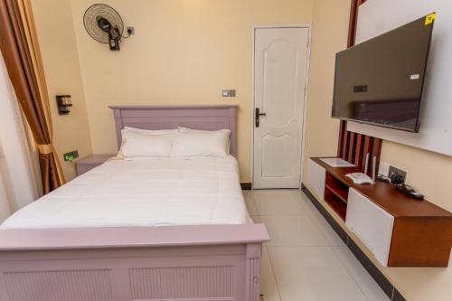 a bedroom with a bed and a flat screen tv at Blanket Suites in Kabubu