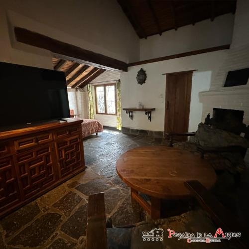 a living room with a tv and a wooden table at Posada de la Mision, Hotel Museo y Jardin in Taxco de Alarcón