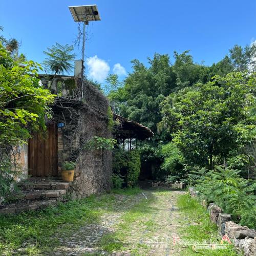 an old stone house with a dirt road and trees at Posada de la Mision, Hotel Museo y Jardin in Taxco de Alarcón