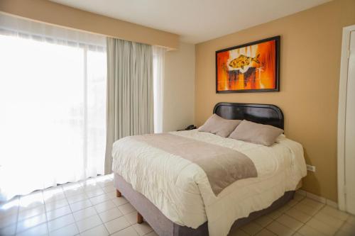 a bedroom with a bed and a painting on the wall at Hotel Santa Fe Los Cabos by Villa Group in Cabo San Lucas