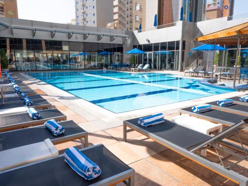 a large swimming pool with lounge chairs in a building at Holiday Inn Kuwait by IHG in Kuwait