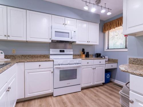 a kitchen with white cabinets and white appliances at Spinnaker at Shipyard in Hilton Head Island