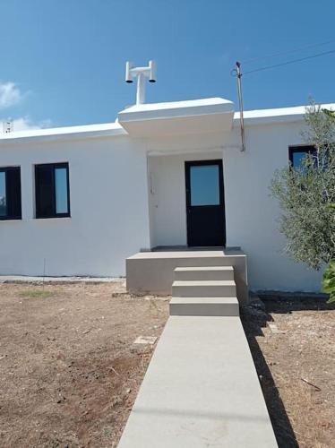 a white building with a pathway leading to a door at Pomos rockaway beach house in Pomos