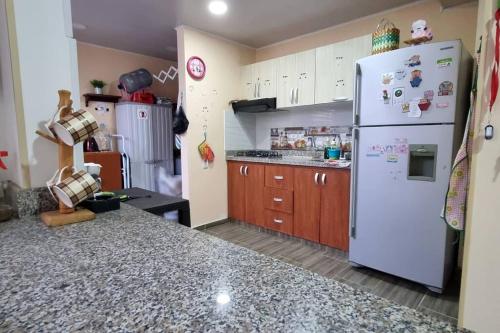 a kitchen with a white refrigerator and wooden cabinets at Acogedora y amplia casa en Anapoima con piscina en condominio cerrado - hasta 8 personas in Anapoima