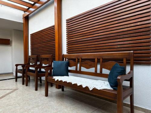 a room with four wooden benches with blue pillows at Casa Aconchegante no Centro de Cianorte in Cianorte