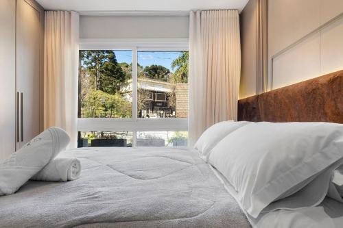 a bedroom with a large bed with a large window at Tribeca 2 Suítes 350m Rua Coberta by Achei Gramado in Gramado