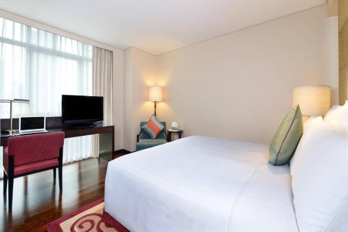 a hotel room with a large white bed and a desk at Sathorn Vista, Bangkok - Marriott Executive Apartments in Bangkok