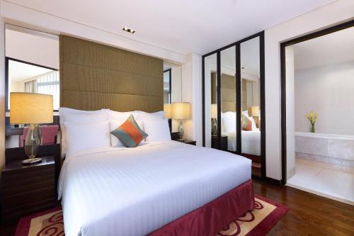 a bedroom with a large white bed and a bath tub at Sathorn Vista, Bangkok - Marriott Executive Apartments in Bangkok