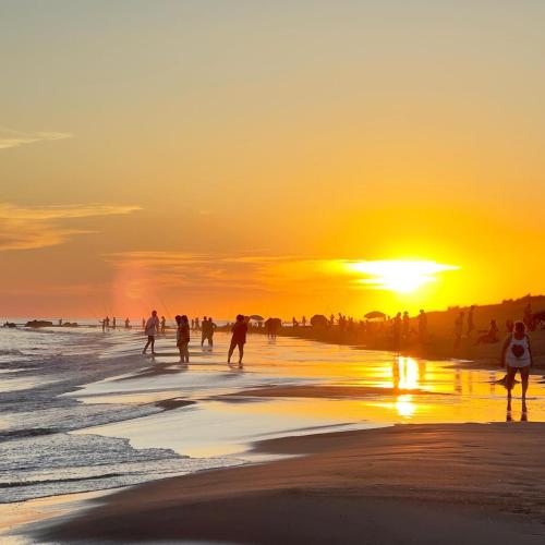 a group of people playing on the beach at sunset at Casitas Atlántida in Atlántida