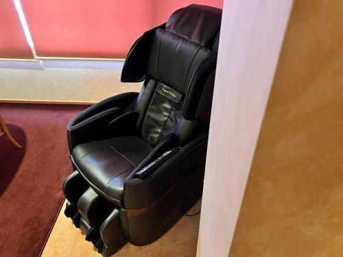 a black office chair sitting next to a wall at Hotel Miki in Gero