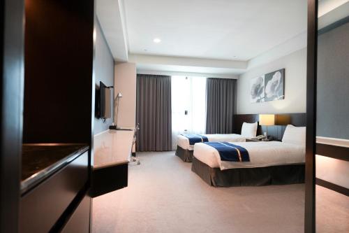 a hotel room with two beds and a television at Hi-YES Hotel Hualien in Hualien City