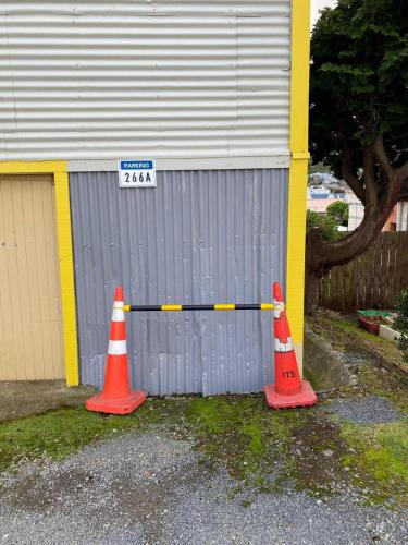 two traffic cones and a street sign in front of a building at Sunny apartment in central Karori in Wellington