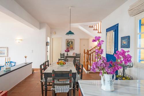 eine Küche und ein Esszimmer mit einem Tisch und lila Blumen in der Unterkunft Sea Front Villa in Naoussa