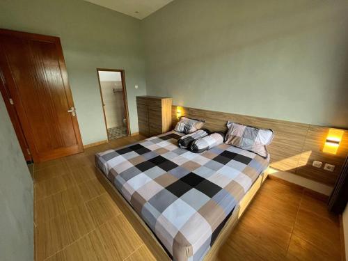 a bedroom with a large bed with a checkerboardkered blanket at Villa makota kota batu in Batu