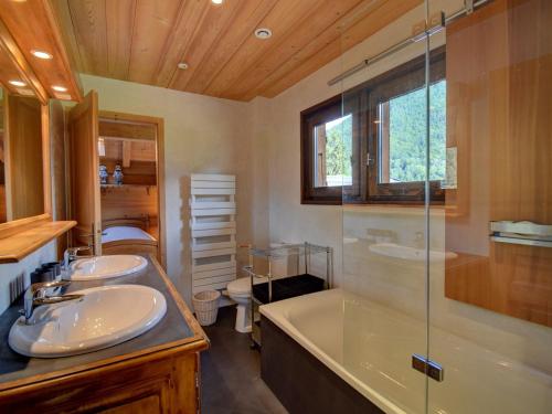 une salle de bain avec deux lavabos, une baignoire et une douche dans l'établissement Superbe Chalet Neuf à Morzine - Cheminée, Terrasse et WiFi - FR-1-524-130, à Morzine