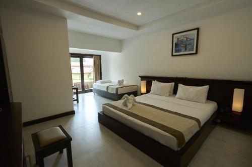 a hotel room with a large bed and a chair at Rajarata Hotel Anuradhapura in Anuradhapura