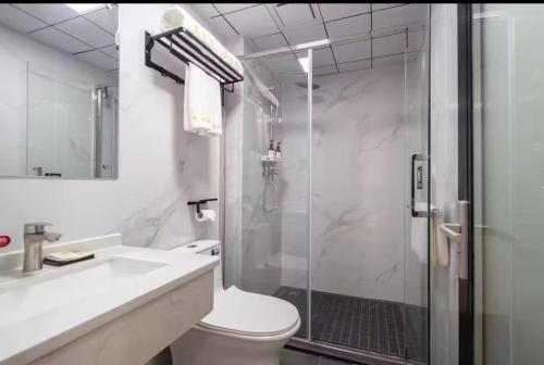 a bathroom with a shower and a toilet and a sink at 三亚观海楼酒店（三亚湾椰梦长廊店） in Sanya
