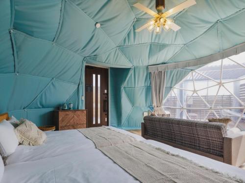 a blue room with a large bed and a ceiling at Seage Torami Coastside in Ichinomiya