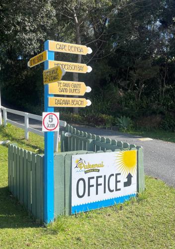 a street sign with many signs on the side of a road at Pukenui Holiday Park in Pukenui
