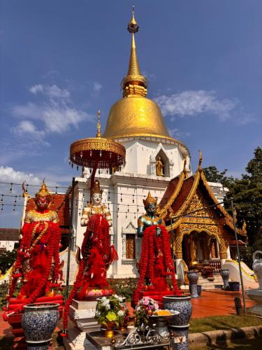 een pagode met twee standbeelden voor een gebouw bij Entire Home with King Bed in Chiang Mai