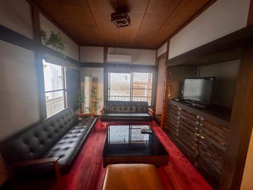 a living room with a couch and a tv at 時端 情緒溢れる西伊豆戸田 人気の古民家一棟貸 ドラッグストア徒歩15秒 海 温泉徒歩5分 自転車2台付 in Toda