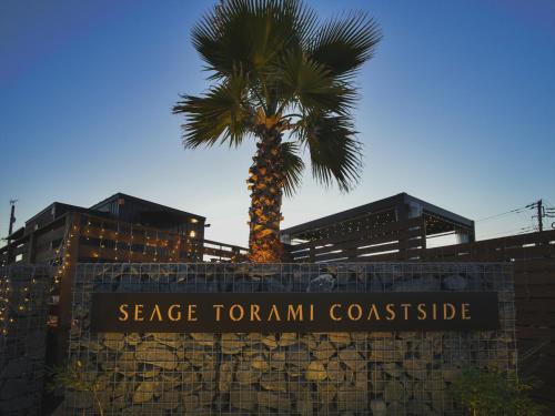 a palm tree in front of a building with a sign at Seage Torami Coastside in Ichinomiya