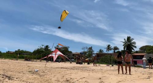a group of people standing on a beach flying kites at Pousada Paraíso Beach in Santa Cruz Cabrália