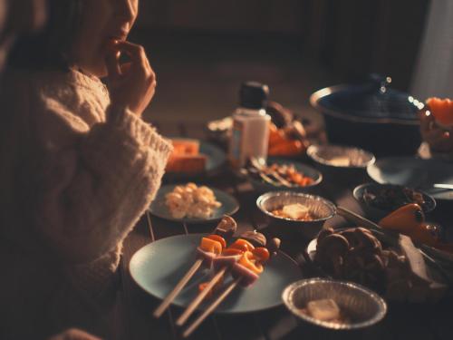 a woman talking on a cell phone next to plates of food at Seage Torami Coastside in Ichinomiya