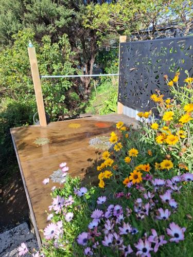 a wooden chair in a garden with flowers at Million Dollar Views in Mangawhai