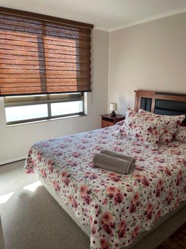 a bedroom with a bed with a floral bedspread at Departamento Aníbal Pinto Concepción in Concepción