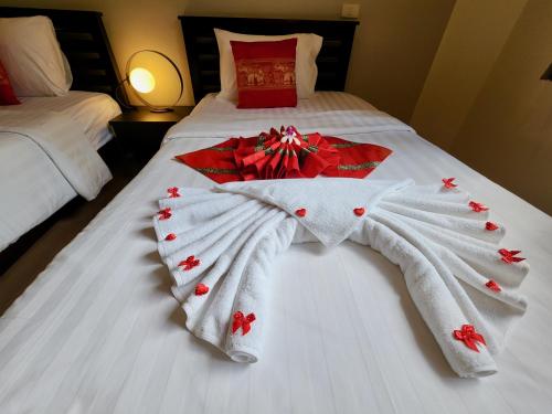 a white blanket with red flowers on a bed at Soleil D'asie Residence in Chaweng Noi Beach