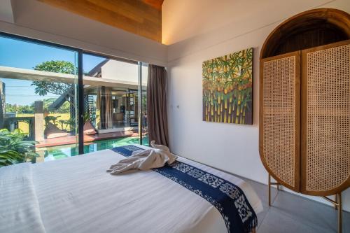 a bedroom with a bed and a large window at Oasis Loft - Ricefield Luxe View Ubud in Ubud