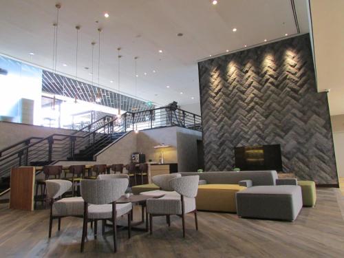 a lobby with tables and chairs and a staircase at Aerotel Singapore - Transit Hotel in Terminal 1 in Singapore