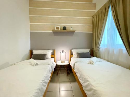 two beds in a room with a lamp on a table at MesaHill Homestay, Nilai by S&T Homez in Nilai
