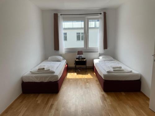 twee bedden in een kamer met een raam bij Buchengasse Apartment Vienna - Free Highspeed-Internet in Wenen