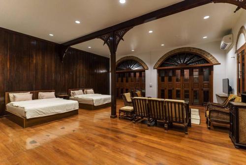 a bedroom with two beds and a tv and wooden walls at FOREST - Fong Lee CC Lampang Walking Street in Lampang