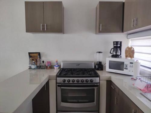 a kitchen with a stove and a microwave at Bonita casa amueblada in Colima