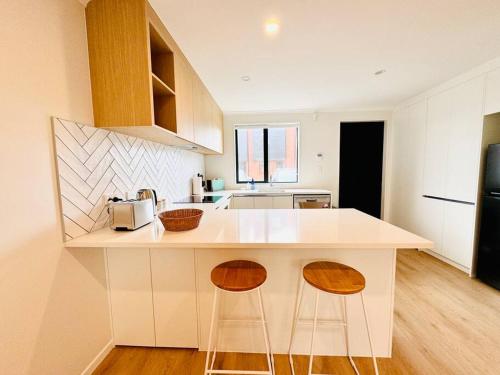a kitchen with a counter and two bar stools at Henderson - 4-Bedrooms Home in Auckland