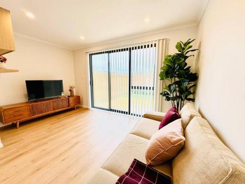 a living room with a couch and a flat screen tv at Henderson - 4-Bedrooms Home in Auckland