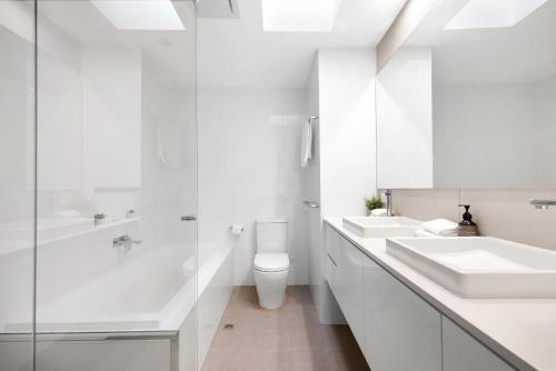 a white bathroom with two sinks and a shower at Moondarah: Pet-Friendly Escape in Noosa Heads