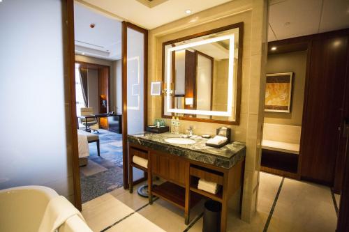a bathroom with a sink and a large mirror at Wyndham Urumqi in Wujiaqu