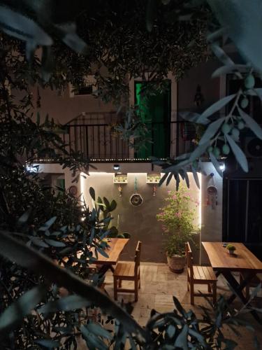 a patio with wooden tables and chairs and a balcony at OTELIA PANSIYON in Ayvalık